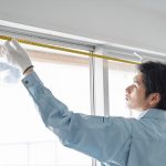 窓枠のサイズを測る日本人男性